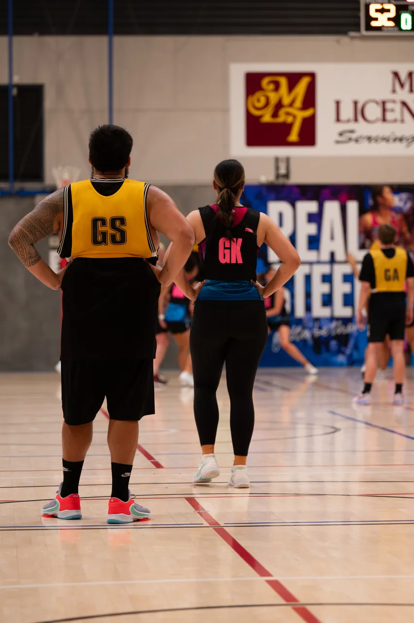 GS and GK players standing on a netball court