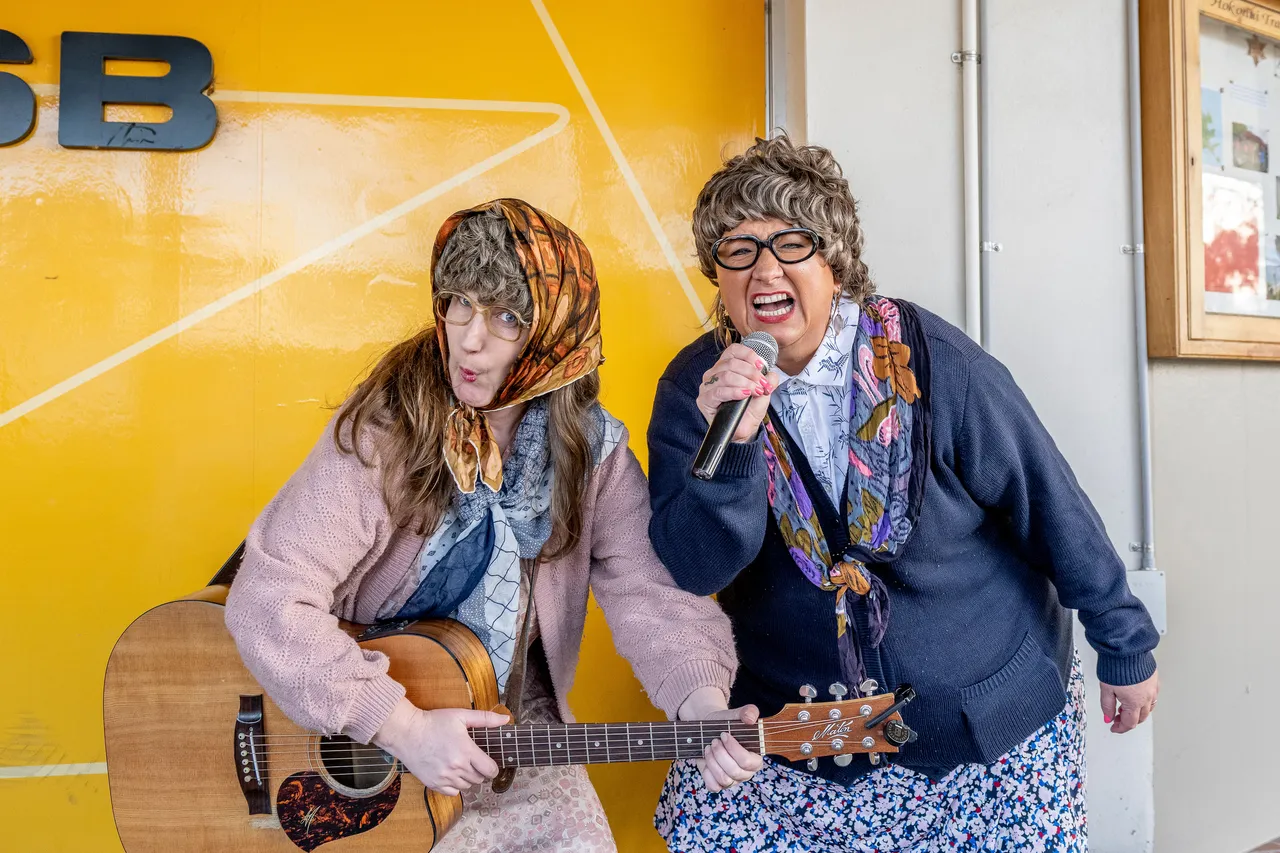 Two women dressed in elderly attire busking