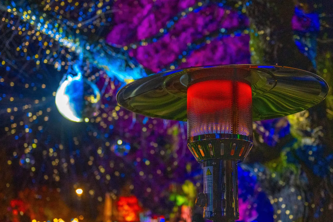 Gas heater illuminated in red with fairy lights and disco ball in background.