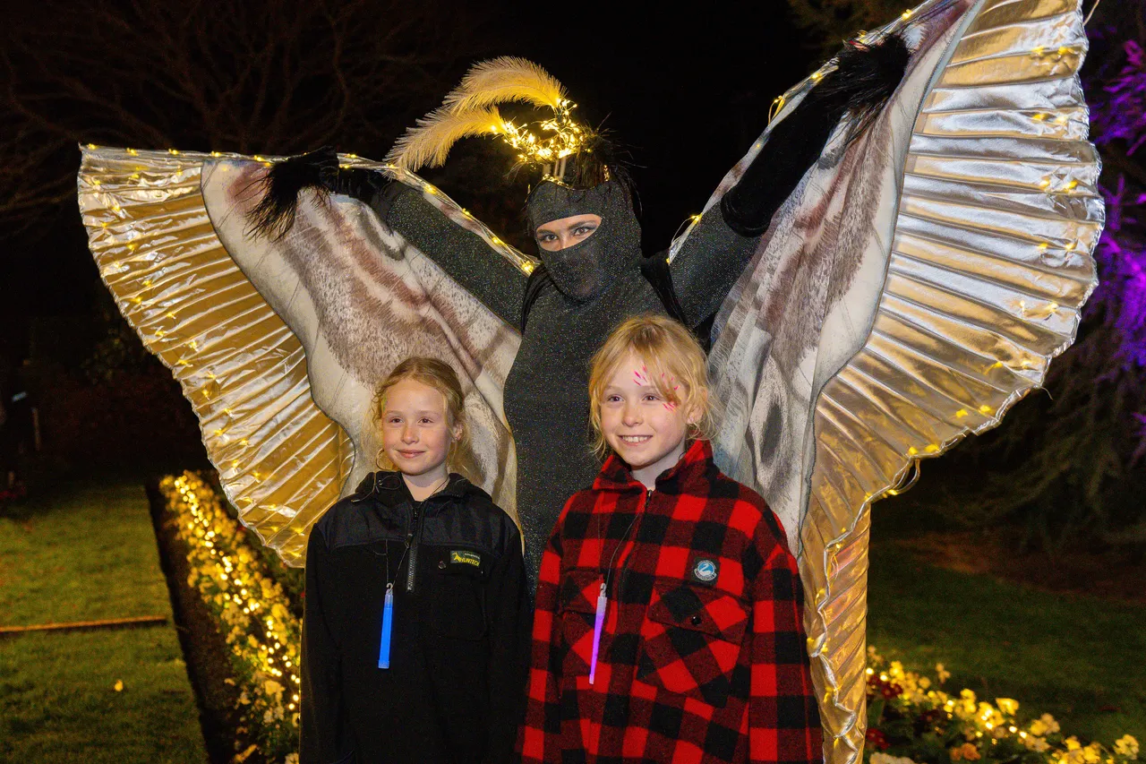 One moth performer standing with two children for photo
