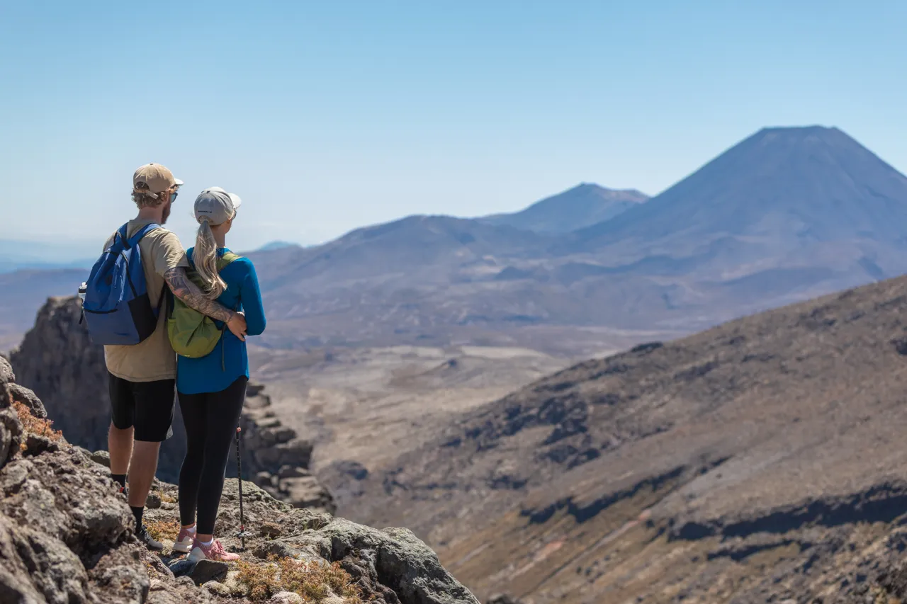 Couple standing on Mt Ruapehu looking at Mt Ngauruhoe