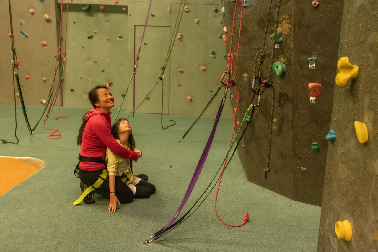 Mother and daughter indoor rock climbing