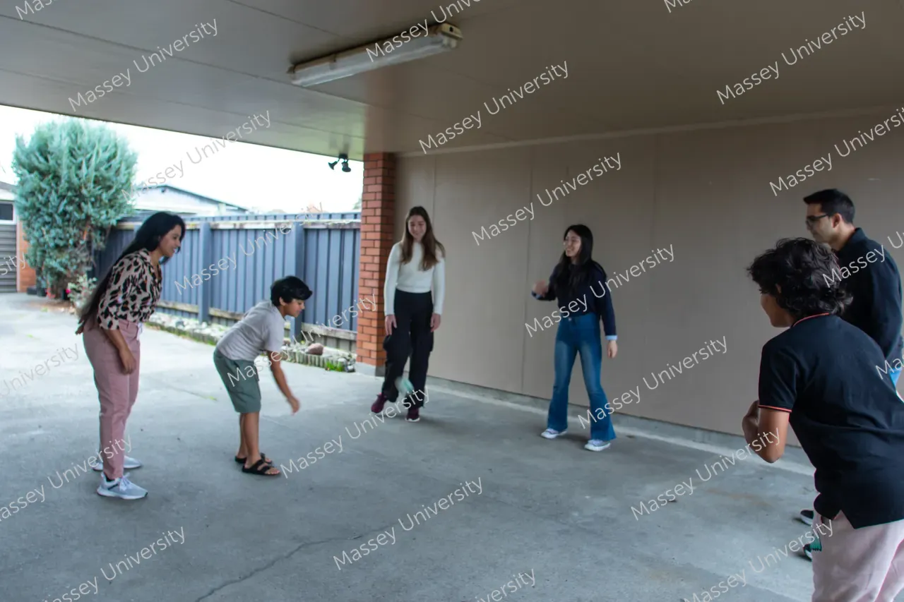 Six people gather in a covered outdoor space as a young man bends forward, preparing for a game.