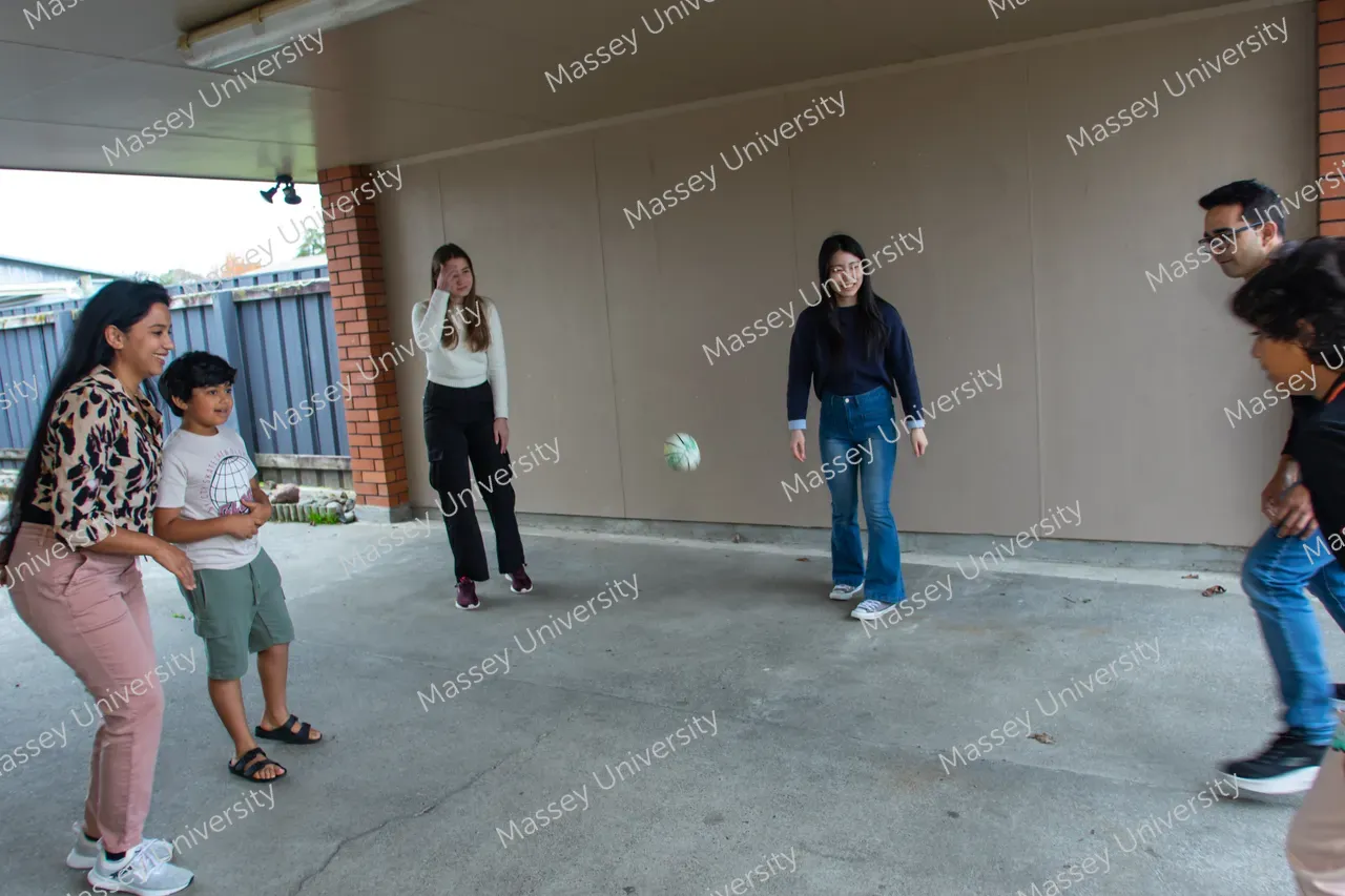 A group of people stand in a covered area as a ball bounces between them.
