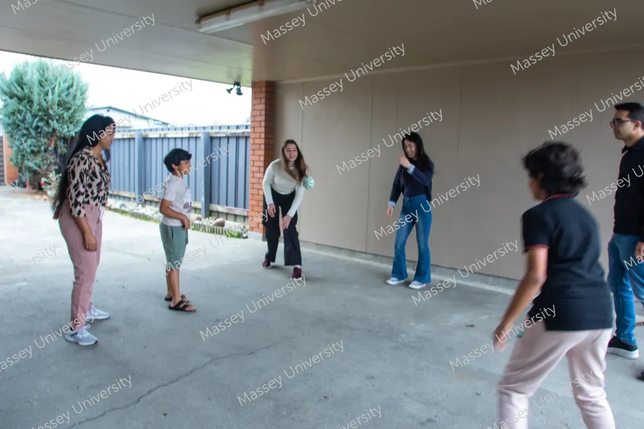 A group of people stand in a circle under a covered area during a ball game.