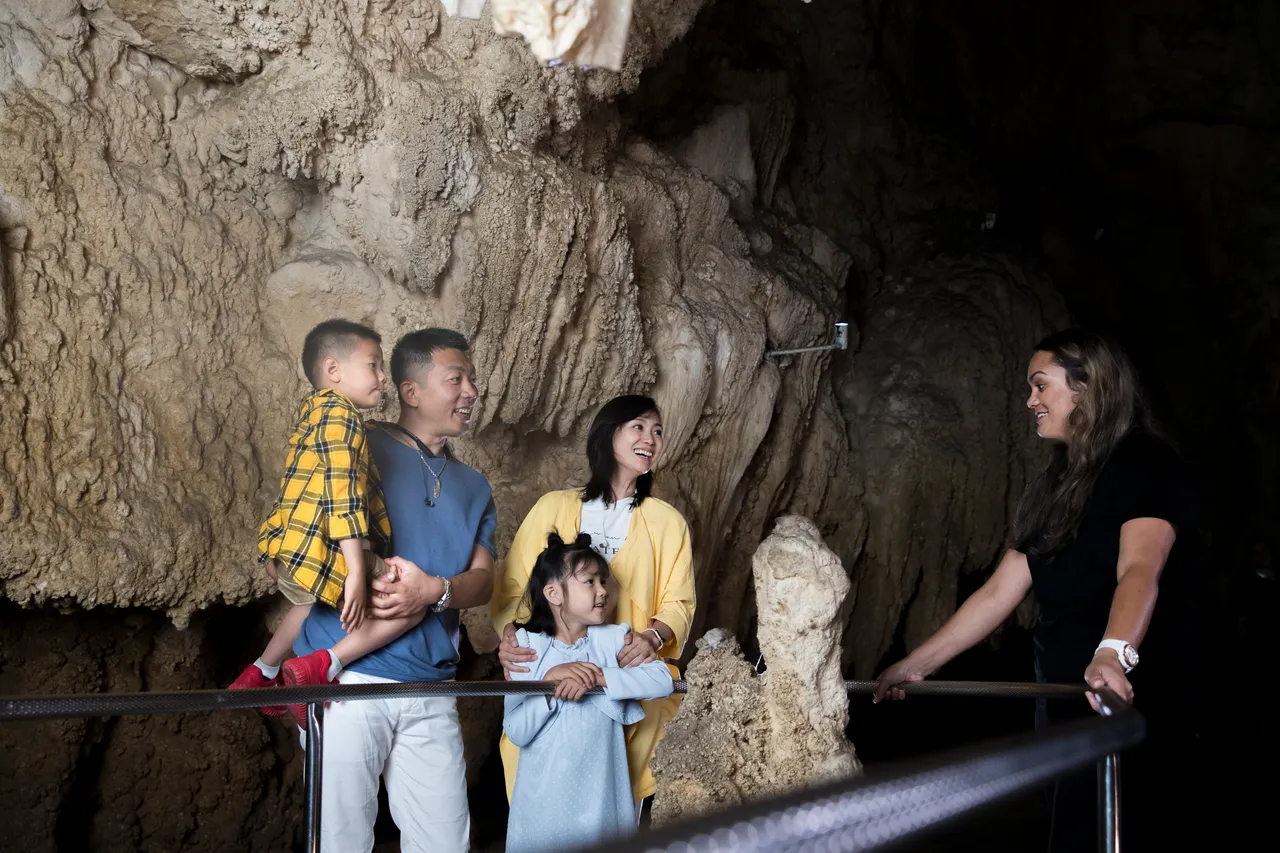 Chinese family & guide in front of limestone formation in Waitomo caves