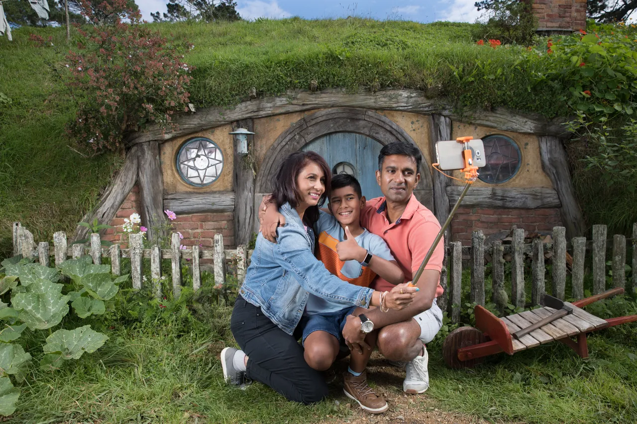 Indian family taking a selfie in front of a Hobbit house