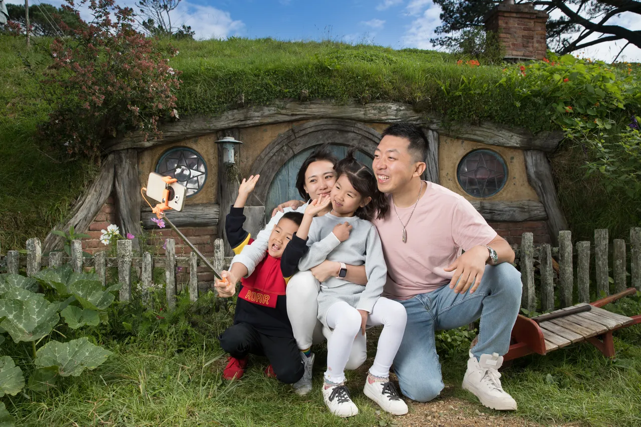 Chinese family taking a selfie in front of a Hobbit house