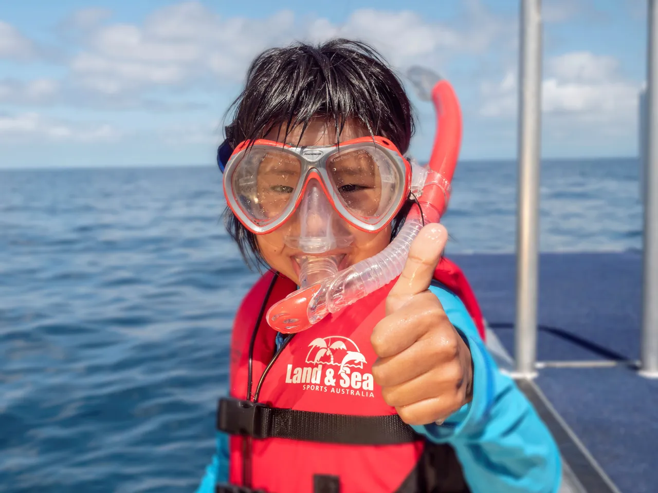 Asian kid with snorkeling gear smiling to the camera