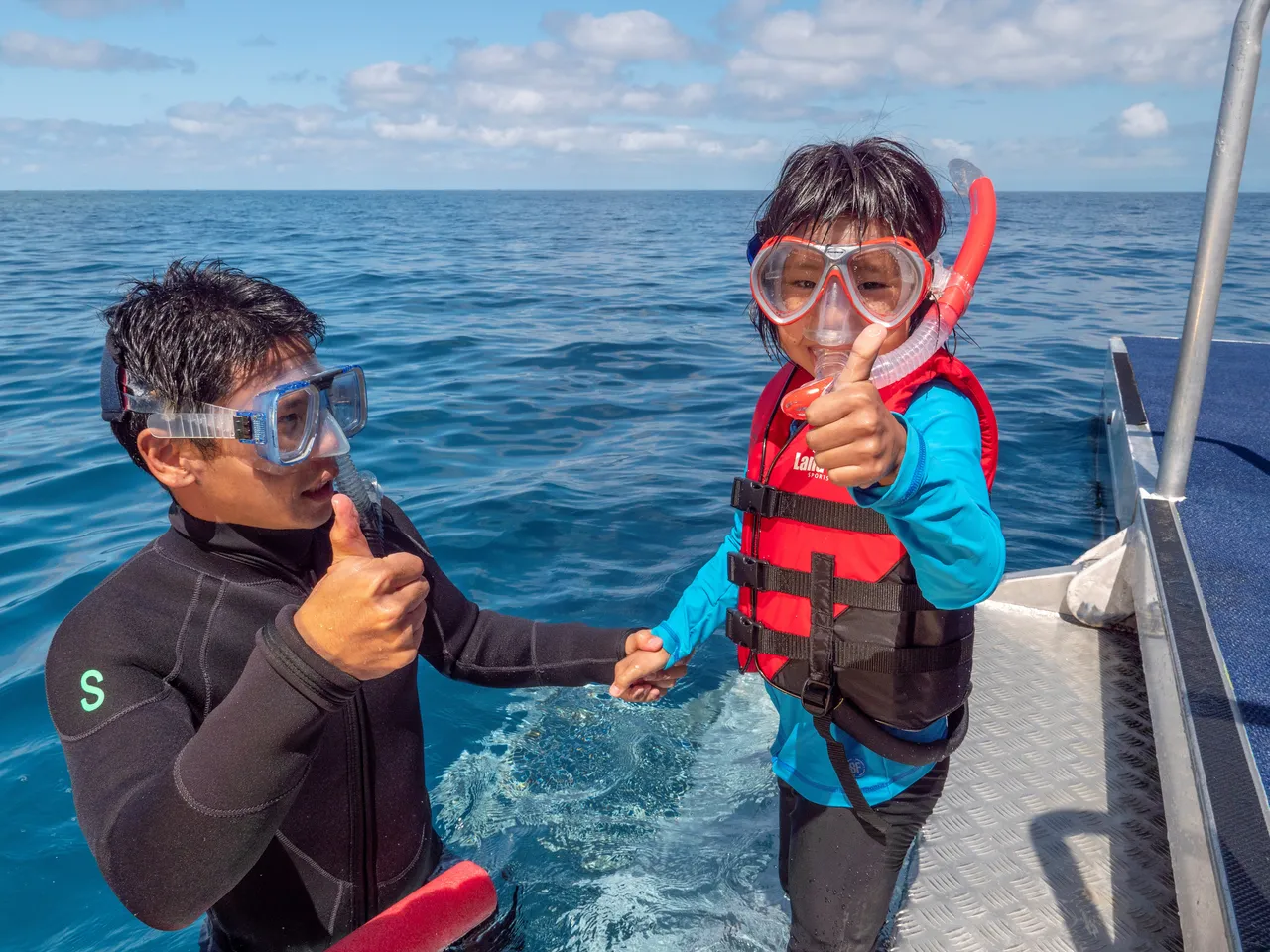 Asian kid with snorkeling instructor smiling to the camera