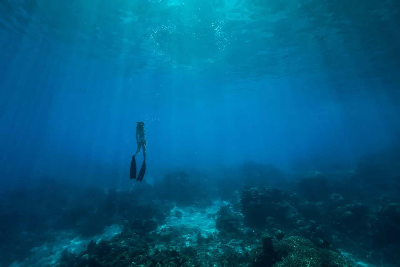 European female snorkeling on a bed of coral reef