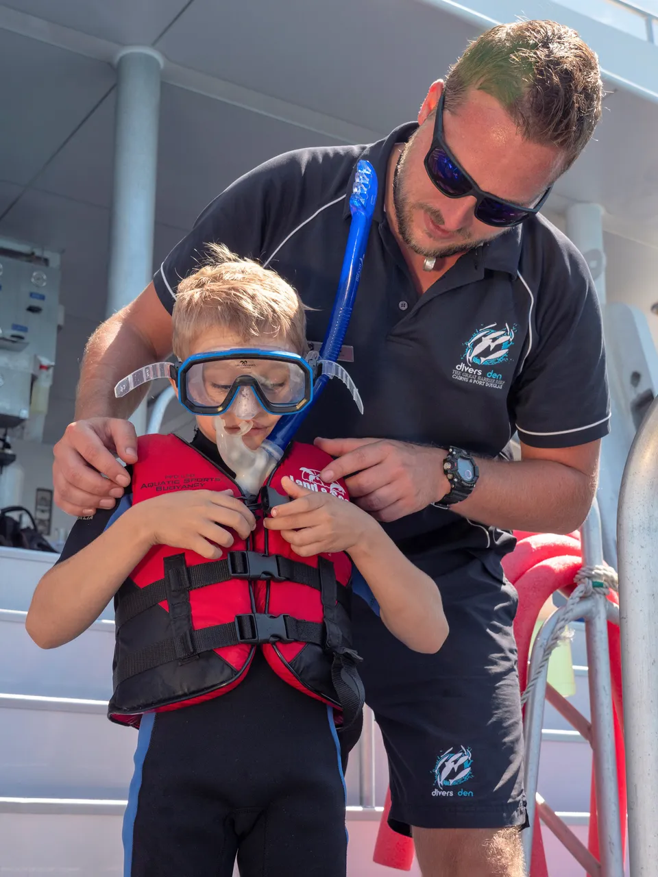 Male staff prepping snorkeling gear of child