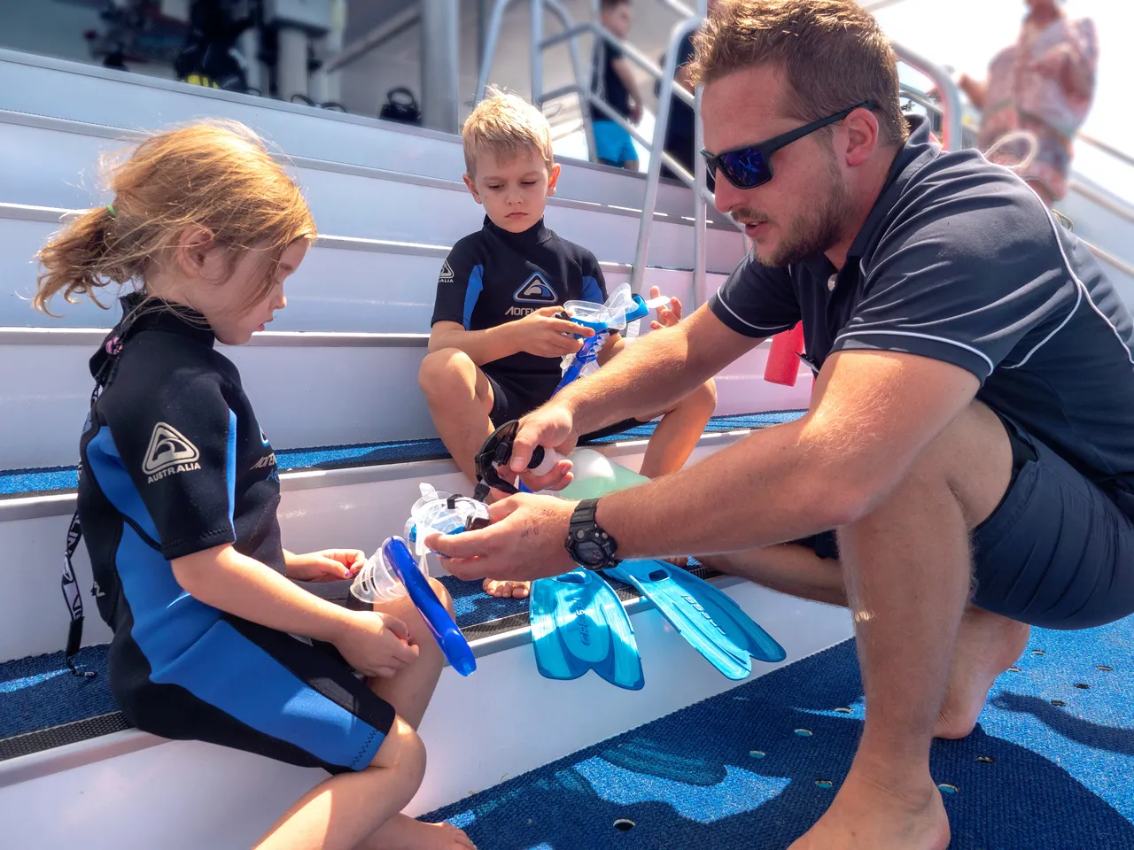 Male staff prepping snorkeling gear of children