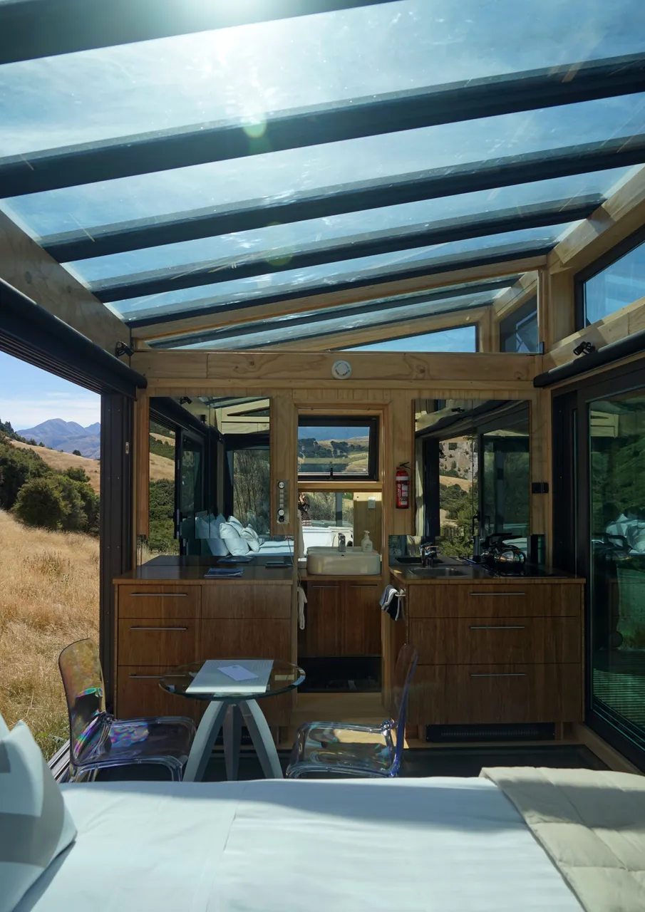 Kahutara PurePod - interior - sun shining through glass ceiling, looking towards the kitchen & bathroom
