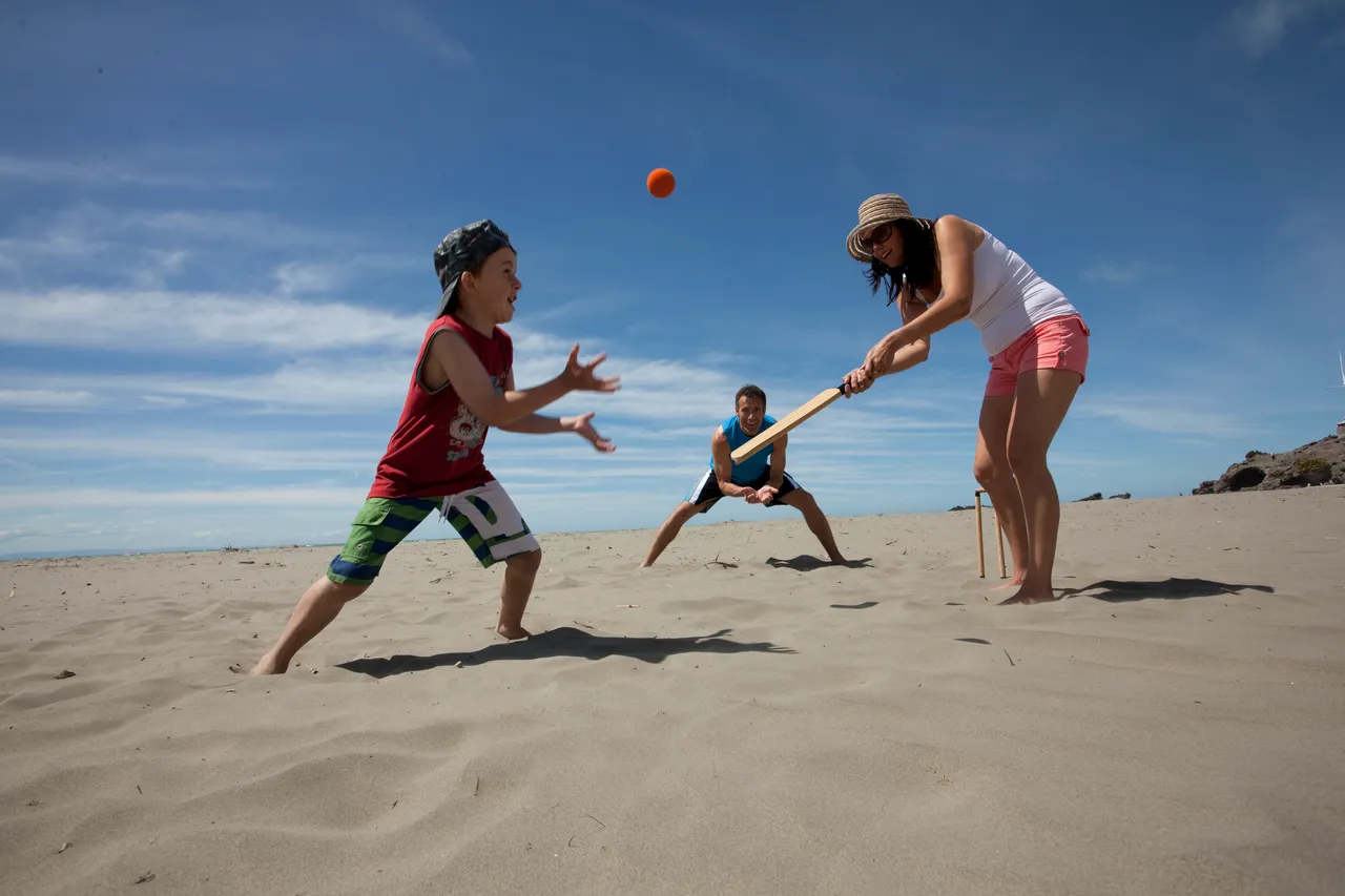 Family playing beach cricket