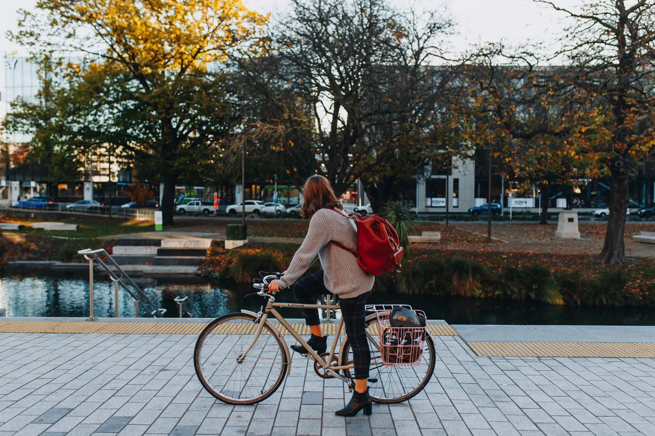 Woman on cycle overlooking Otakaro Avon River in Autumn