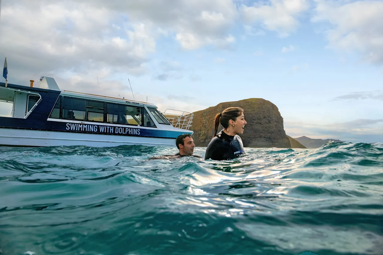 Couple swimming with dolphins with Black Cat Cruises